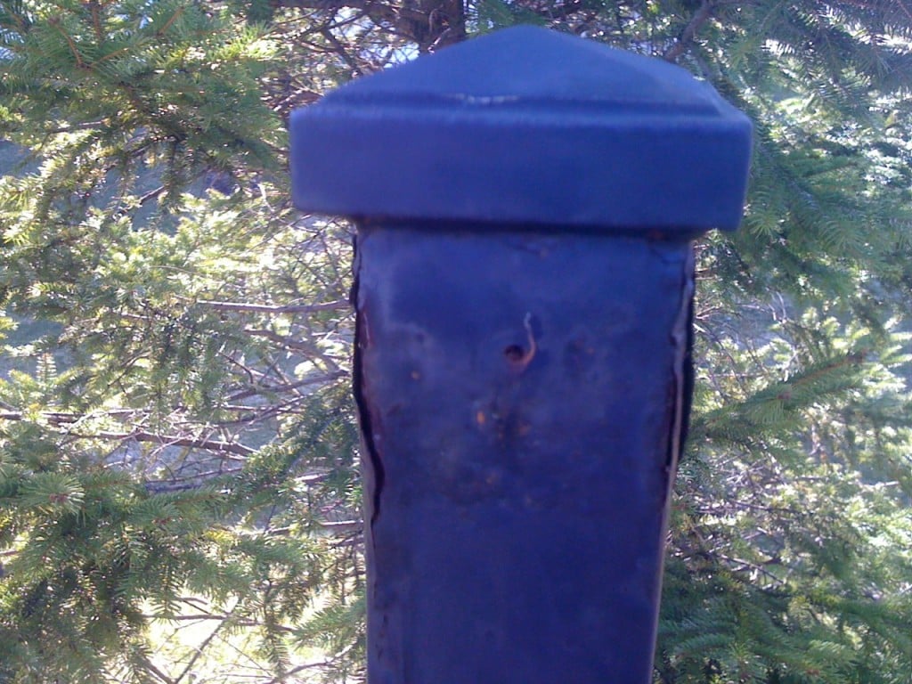 A Non-Galvanized Iron Fence Post Rusting from Below the Finish Causing it to Blister and Come Off