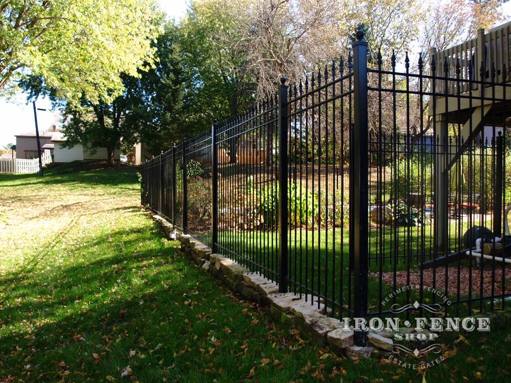 Iron Fence Installed on a Gentle Hill with Stone Underneath