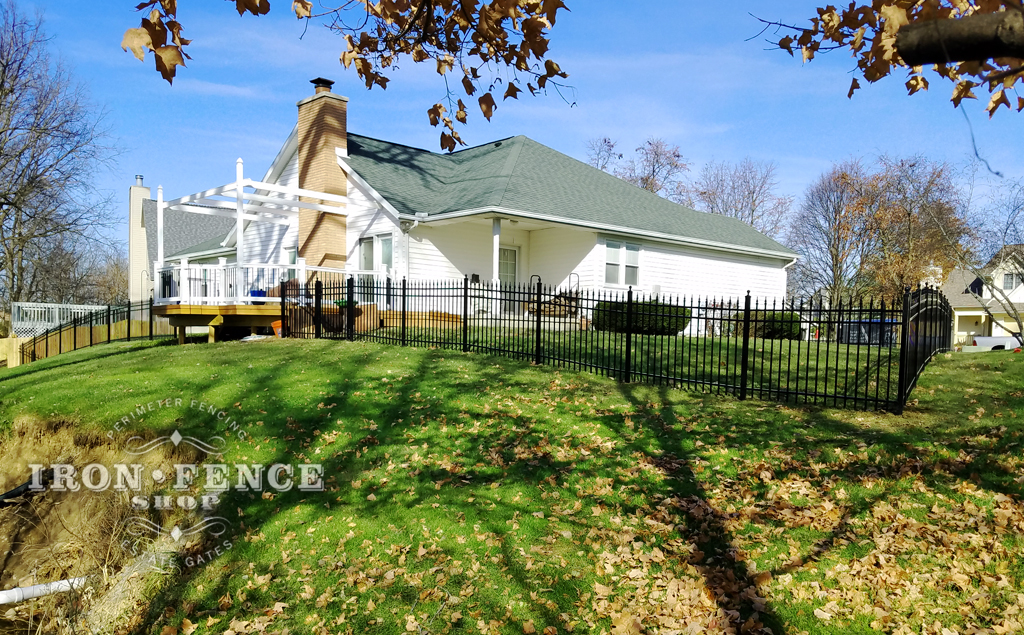 white house with black iron fencing enclosing the backyard 